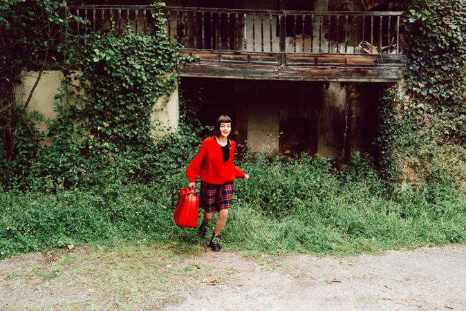 Woman in red with big red suitcase in forest