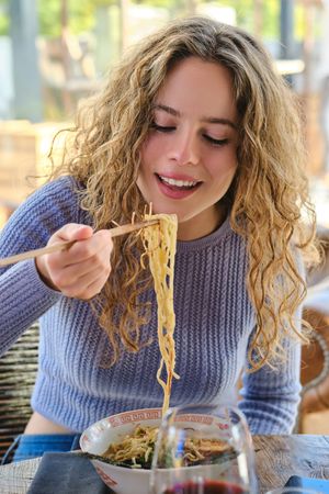 Young female enjoying delicious ramen in modern restaurant