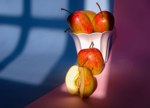 Photo of an apple in a container on a pink and blue background