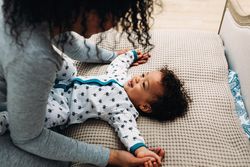 Cute baby boy lying down looking up at mother holding his hands