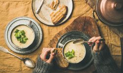 Woman with spoon and celery soup in cup