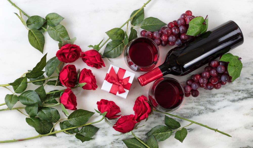 Romantic setting with red wine and roses on marble stone