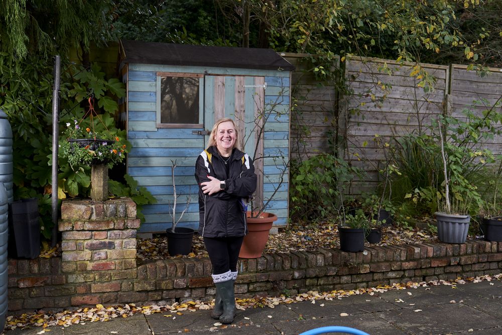 Woman with arms crossed outside blue wooden hut