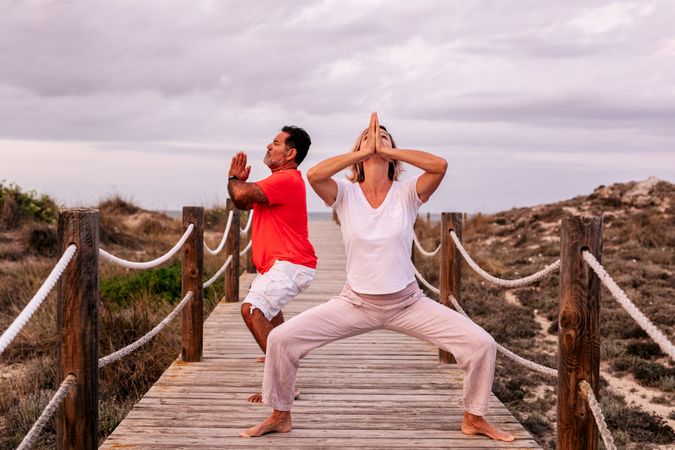 Adult couple meditating on wooden path
