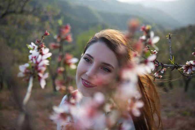 Young happy woman between trees in garden