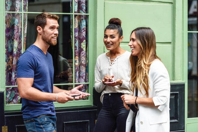 Multiracial group of friends chatting next to green wall outside