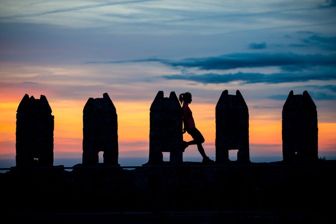 Silhouette of person between stone sculptures in sunset