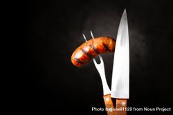Fork piercing a grilled sausage and knife with space for text 4B16x5