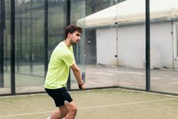 Young man playing paddle tennis on a green court