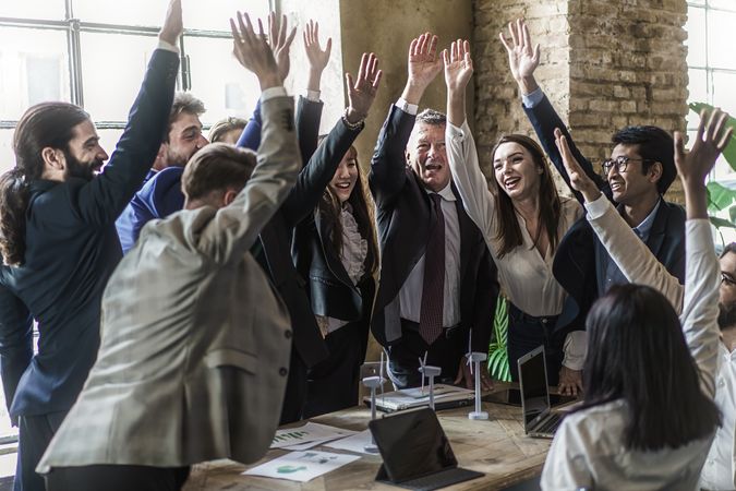 Successful multiracial businesspeople cheering raising hands