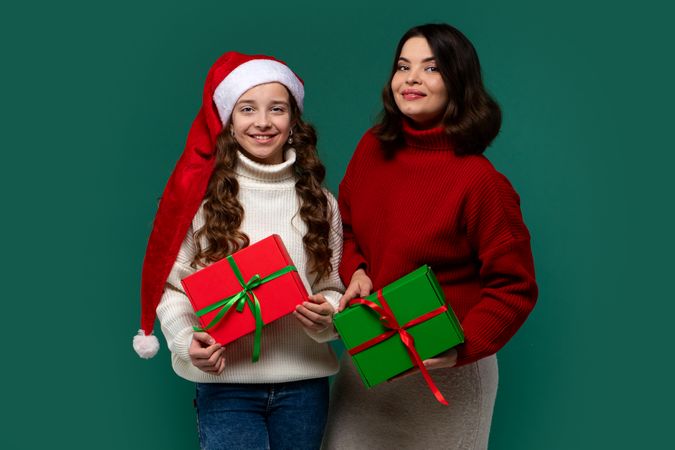 Mum and teenage daughter hold red and green gift boxes happily