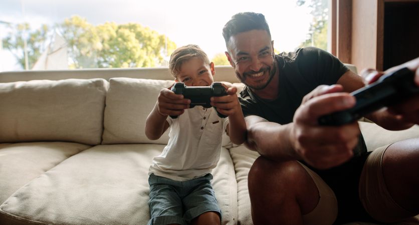 Portrait of father and son enjoying playing video game in living room