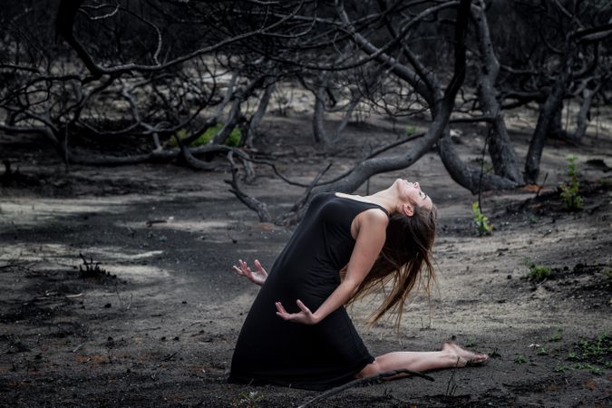 Woman posing on ground near dry trees