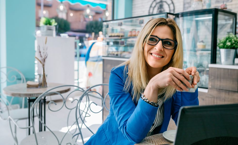 Woman drinking coffee and using laptop