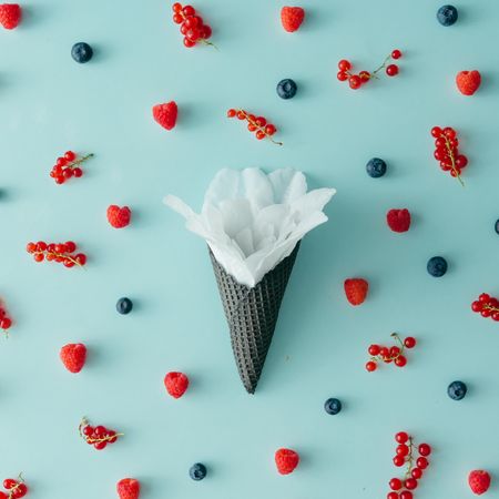 Flower in dark waffle cone on blue background with berries