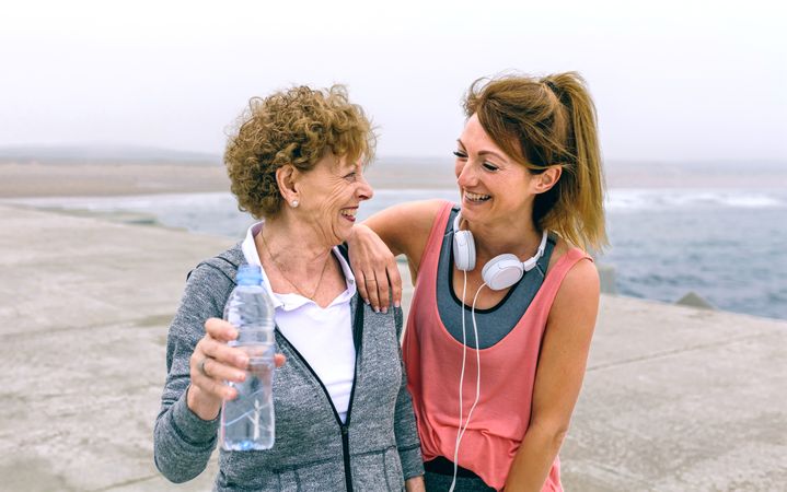 Sportswomen laughing together near ocean