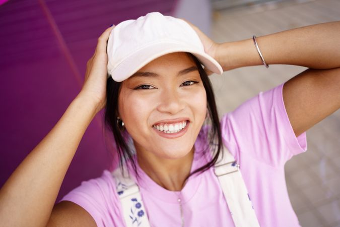 Smiling Chinese female looking up at camera near pink wall outside