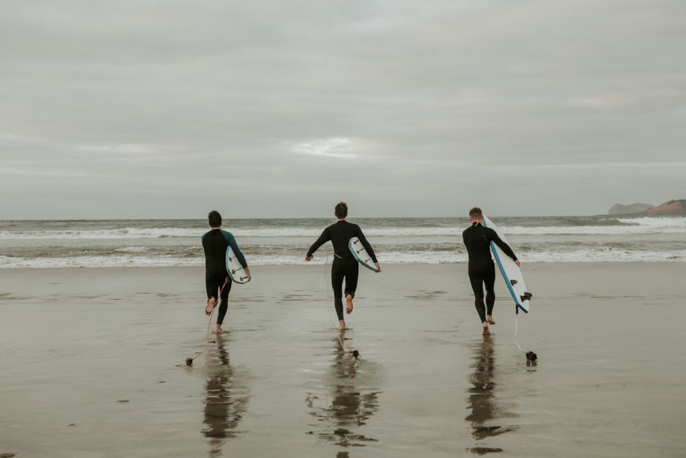 People with surfboard walking near sea