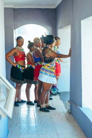 Zulu wedding guests wearing traditional beaded attire and headdresses gather in a hallway