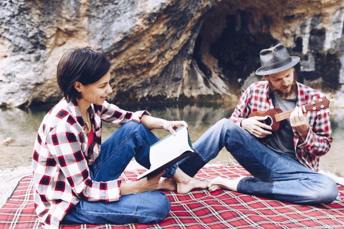 Chilling couple with book and guitar on shore