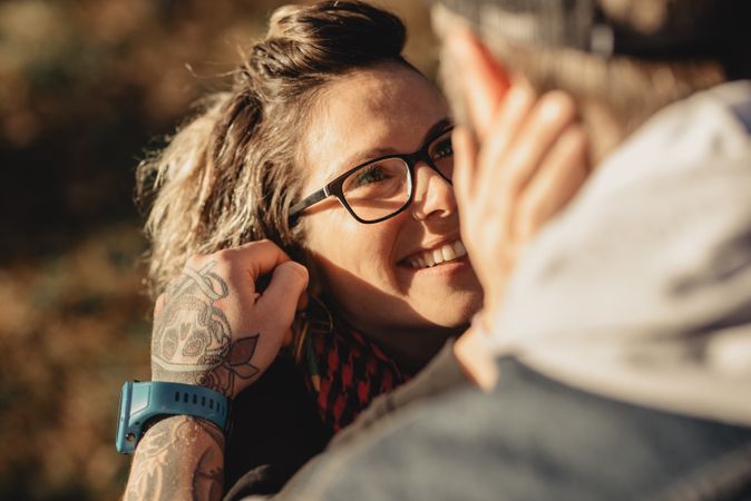Happy couple hugging and kissing near tree in park