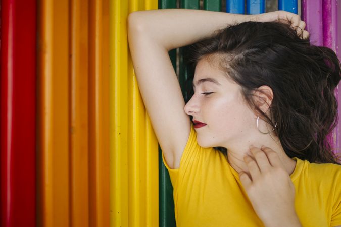 Cheerful woman lying down on rainbow bench back ground