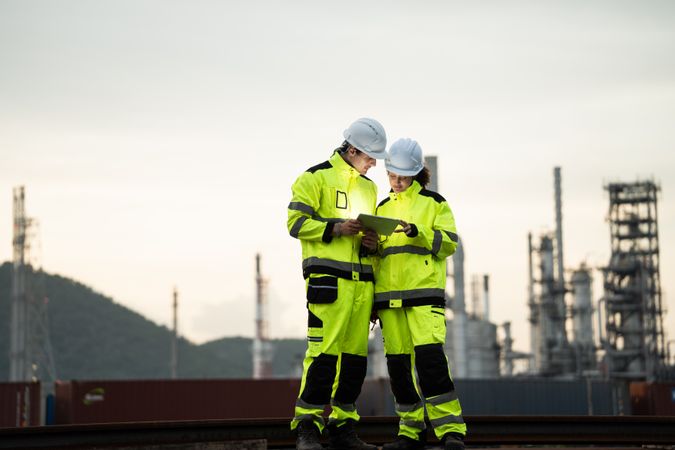 Engineer worker watching work monitor on digital tablet at refinery factory at night