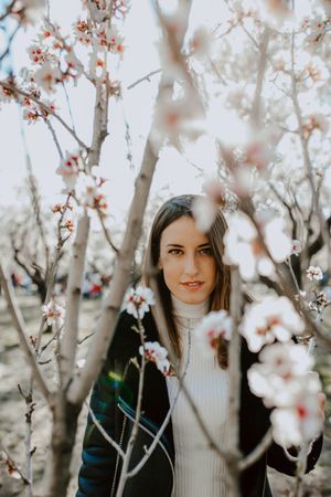 Young happy woman between trees in garden