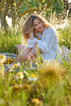 Smiling woman sitting on plaid in abundant park