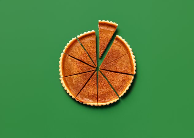 Sliced pumpkin pie, top view on a green table