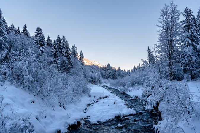 Winter landscape with river flowing through the snow-covered forest in Bavaria, Germany