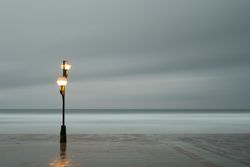 Landscape of blurry quay near calm sea and cloudy sky