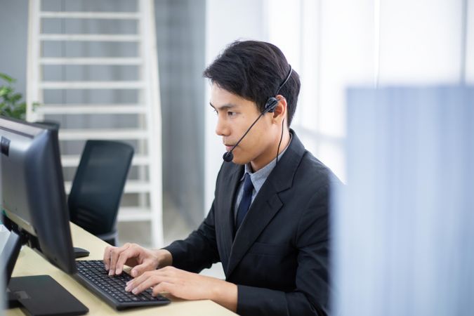 Man at work wearing headset sitting at laptop