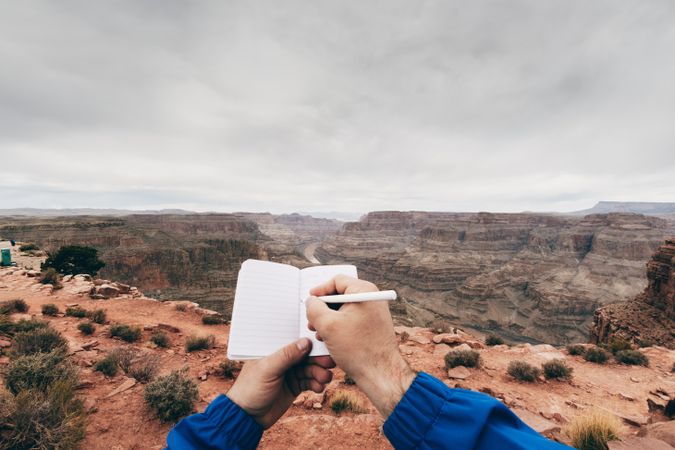 Male drawing in notebook at rock