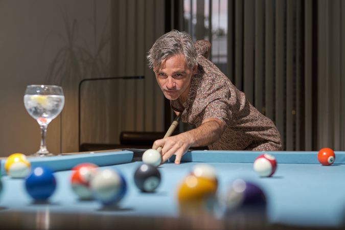 Handsome man leaning over the table while playing pool
