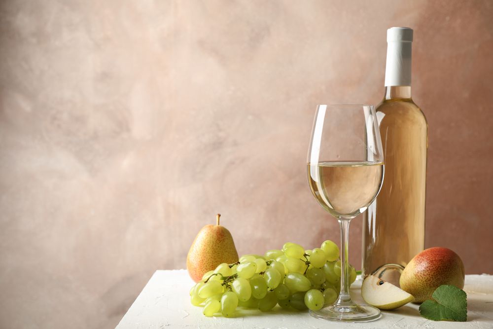 Pears, grape, bottle and glass with wine on blank background, copy space