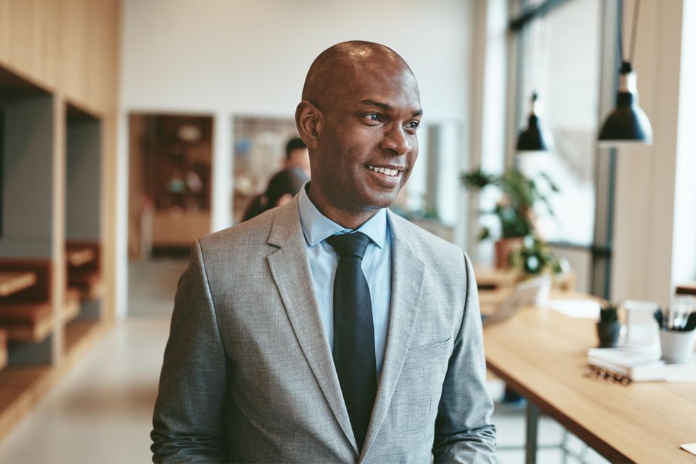 Business man standing and smiling in open office