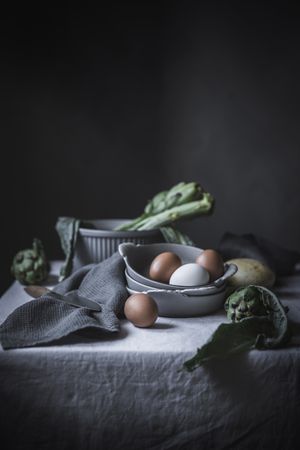 Eggs and different herbs in bowls placed on rustic table