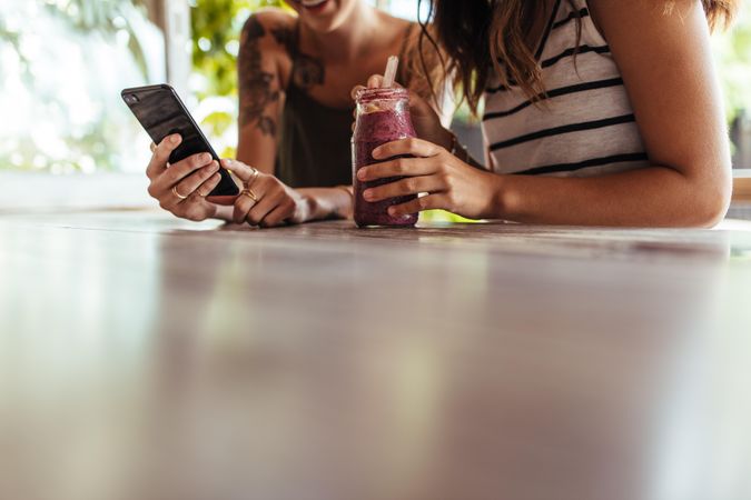 Close up of two women sitting at a restaurant looking at mobile phone