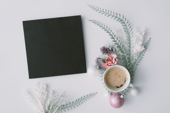 Coffee and dark paper card with flowers, leaves and pink Christmas decoration