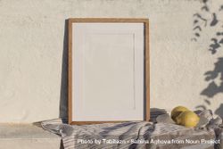 Blank vertical wooden frame picture mock up in sunlight with cotton throw, blanket and fresh lemons 4Zen69