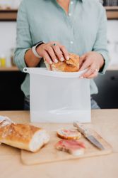 Cropped image of a person putting ham sandwich in plastic bag 5qKyYb