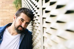 Man leaning head on textured wall outside