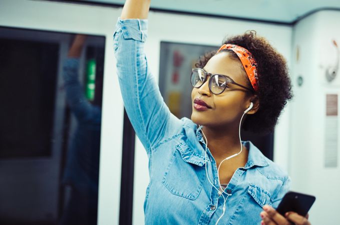 Woman on public transport listening to much in earbuds