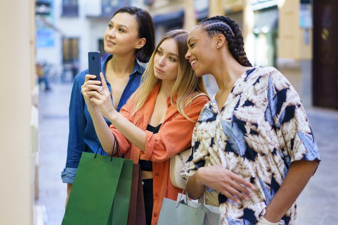 Happy women on shopping trip taking picture of storefront