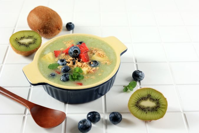 Breakfast Kiwi Smoothie Bowl Topped with Oat Flakes, Pineapple,  and Berries