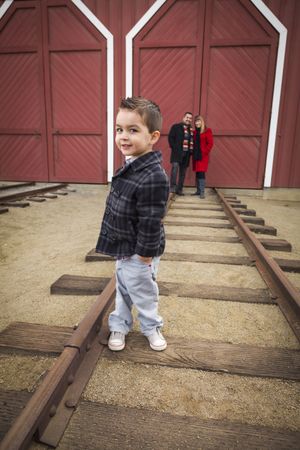 Boy at Train Depot with Parents Smiling Behind