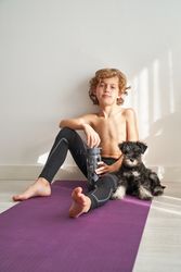Relaxing fit child sitting on mat with puppy