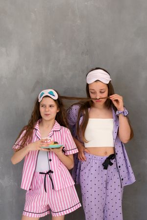 Two girls in striped pajamas playing with hair at a sleepover.