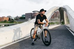Cheerful man with bicycle standing on footbridge